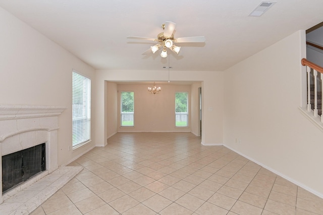 unfurnished living room featuring a premium fireplace, ceiling fan with notable chandelier, and light tile patterned floors