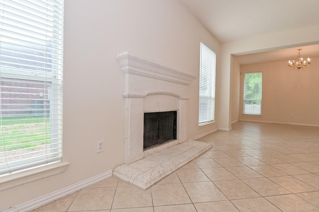 unfurnished living room featuring a notable chandelier, a wealth of natural light, a high end fireplace, and light tile patterned flooring