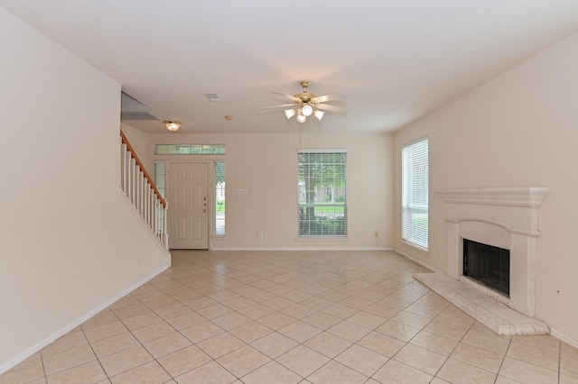 unfurnished living room featuring light tile patterned floors, a high end fireplace, a wealth of natural light, and ceiling fan