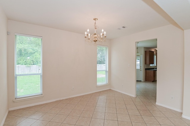 tiled spare room featuring a chandelier