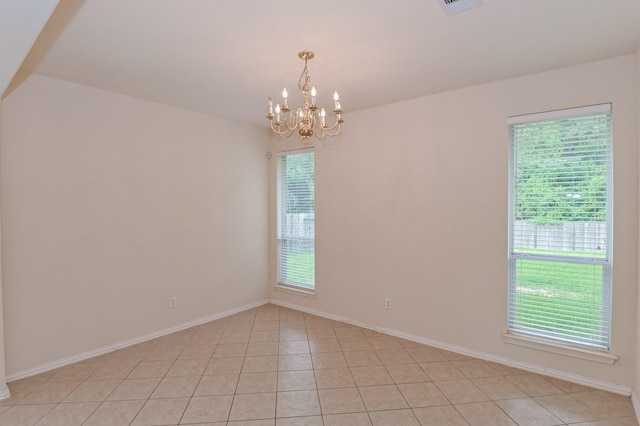 tiled spare room with a notable chandelier