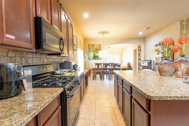 kitchen with light tile patterned floors, pendant lighting, light stone countertops, decorative backsplash, and black appliances