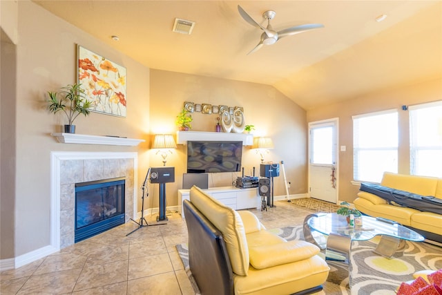 living room with ceiling fan, lofted ceiling, a tile fireplace, and light tile patterned floors