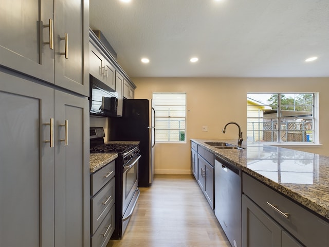 kitchen featuring a sink, plenty of natural light, stone countertops, and stainless steel appliances