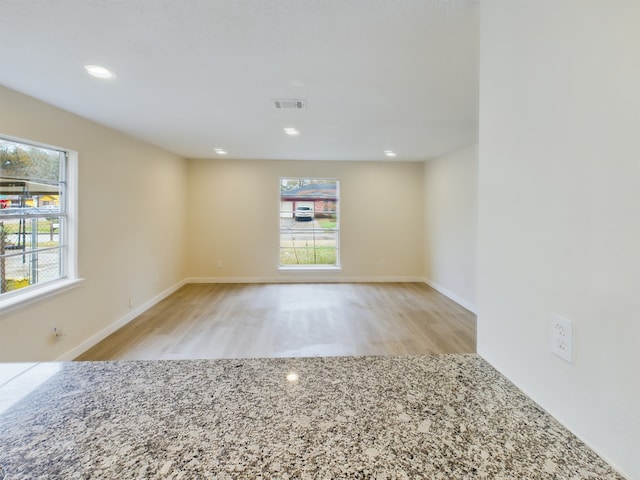 spare room featuring recessed lighting, plenty of natural light, wood finished floors, and visible vents