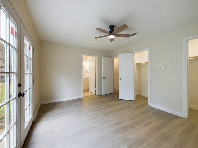 unfurnished bedroom with a spacious closet, visible vents, light wood finished floors, baseboards, and french doors