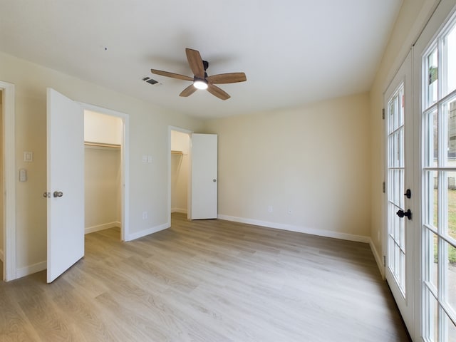 unfurnished bedroom with visible vents, a ceiling fan, light wood-style floors, baseboards, and a spacious closet