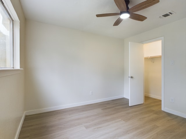 unfurnished bedroom with light wood finished floors, visible vents, a spacious closet, baseboards, and a closet