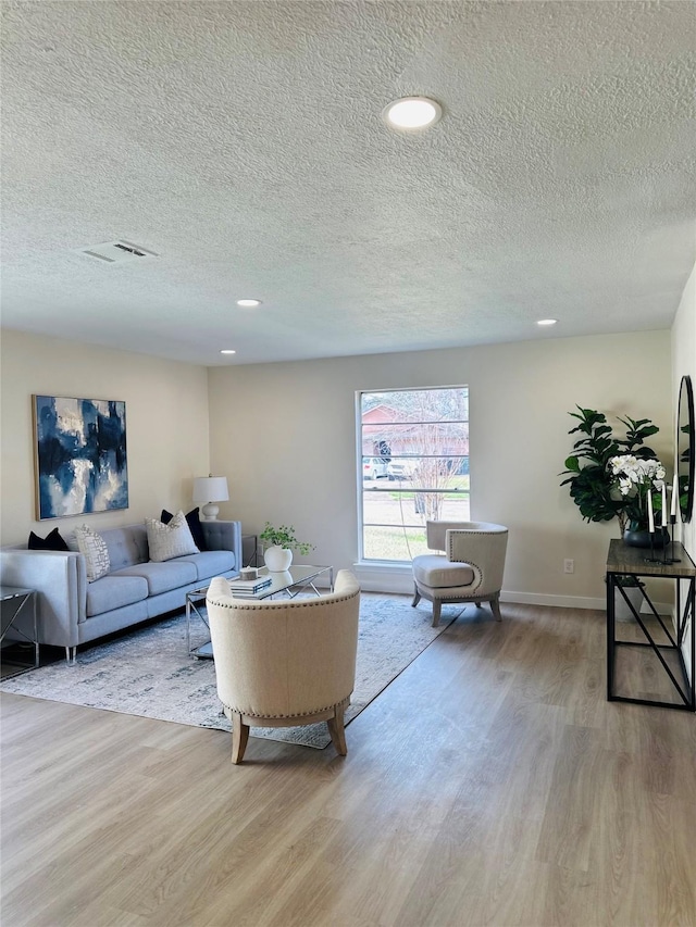 living room with recessed lighting, visible vents, baseboards, and light wood-style floors