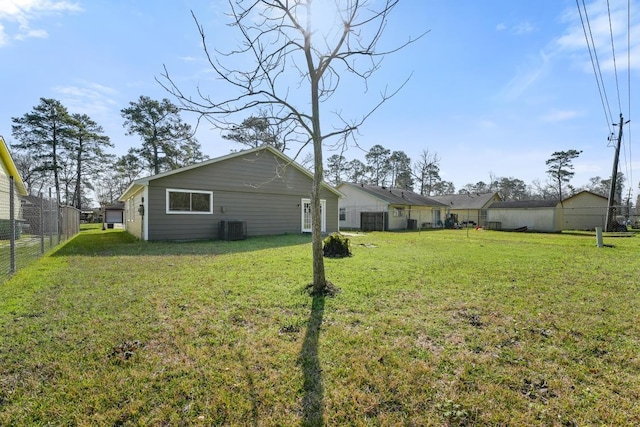 rear view of property featuring a lawn, central AC unit, and fence