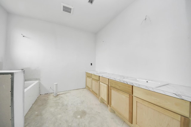 bathroom featuring vanity, a washtub, and concrete floors