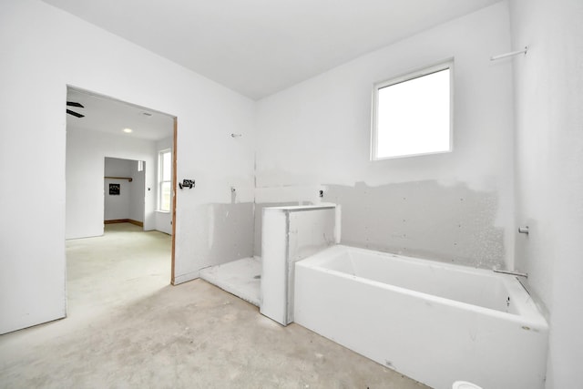 bathroom with a washtub and concrete floors