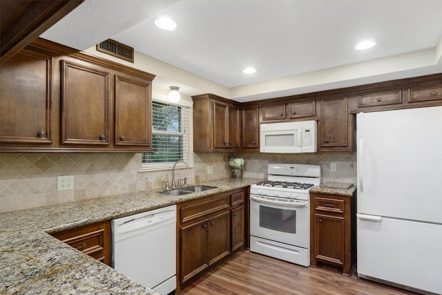 kitchen featuring sink, white appliances, dark hardwood / wood-style floors, and light stone countertops