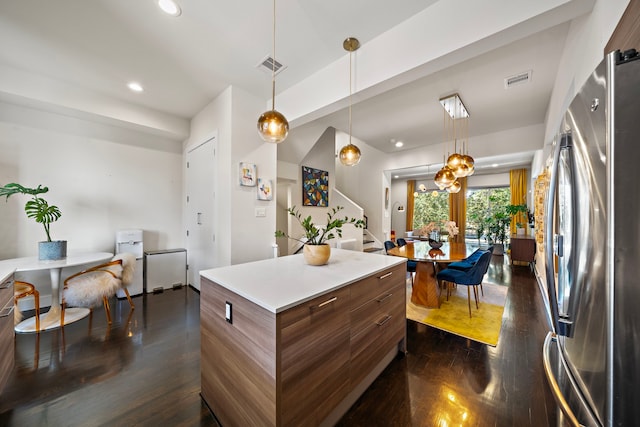 kitchen with pendant lighting, stainless steel fridge, dark hardwood / wood-style flooring, and a kitchen island