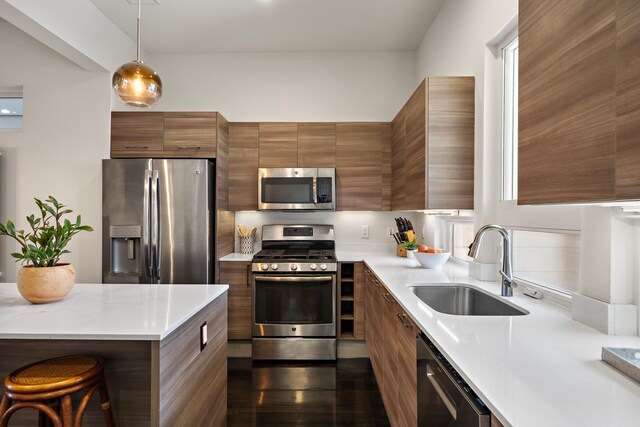 kitchen with sink, hanging light fixtures, stainless steel appliances, and a kitchen breakfast bar