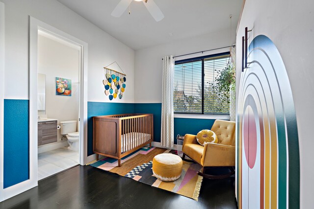 bedroom featuring a nursery area, ceiling fan, ensuite bathroom, and hardwood / wood-style floors