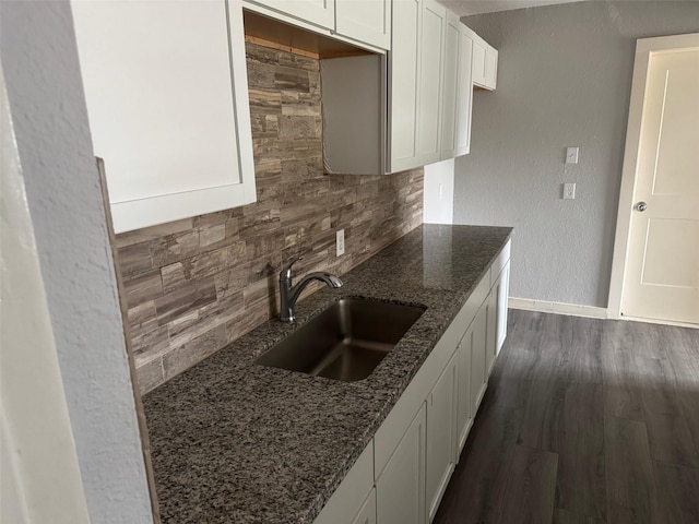 kitchen with white cabinetry, sink, tasteful backsplash, and dark stone counters