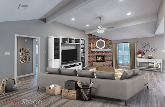 living room featuring ceiling fan, wood-type flooring, a fireplace, and lofted ceiling with beams