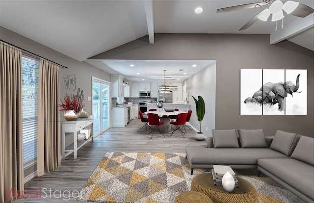 living room featuring lofted ceiling with beams, ceiling fan, and light hardwood / wood-style flooring