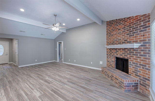 unfurnished living room featuring a brick fireplace, lofted ceiling with beams, light hardwood / wood-style floors, and ceiling fan