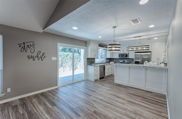 kitchen featuring sink, white cabinetry, light wood-type flooring, stainless steel appliances, and decorative backsplash