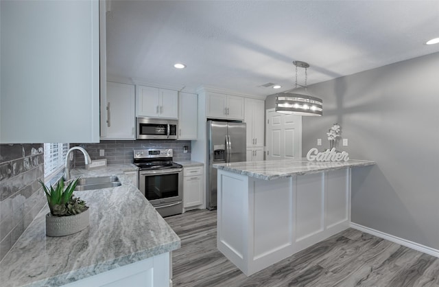 kitchen with sink, hanging light fixtures, stainless steel appliances, white cabinets, and decorative backsplash