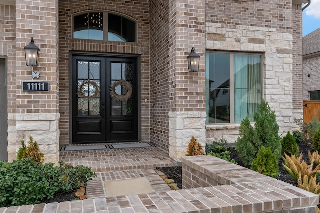 doorway to property featuring brick siding, stone siding, and french doors