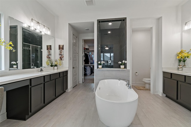 bathroom with a freestanding tub, toilet, vanity, visible vents, and a stall shower