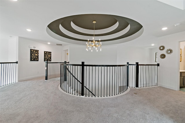 hall featuring a chandelier, a raised ceiling, and light carpet