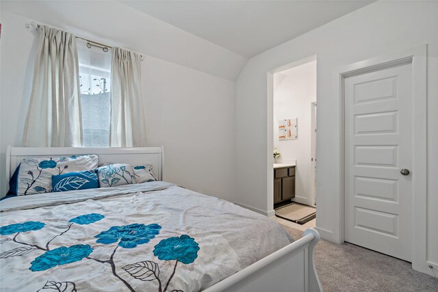 carpeted bedroom featuring lofted ceiling and connected bathroom