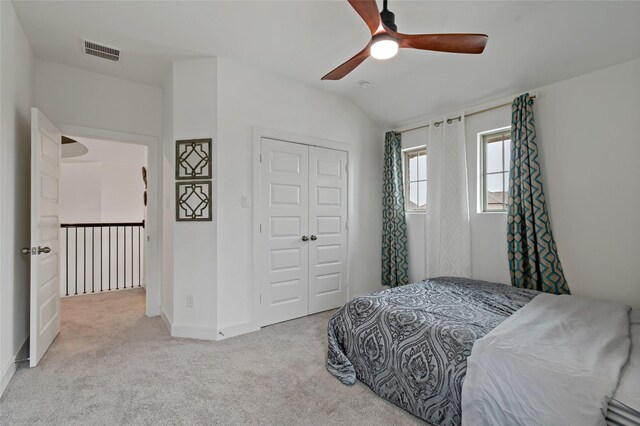 carpeted bedroom featuring ceiling fan, vaulted ceiling, and a closet