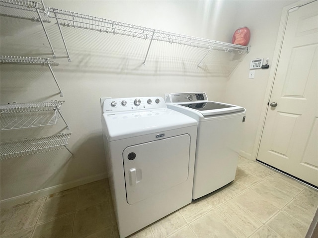 laundry room with washer and clothes dryer, laundry area, and light tile patterned floors