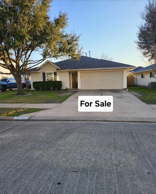 ranch-style house featuring a garage, central AC, and a front lawn