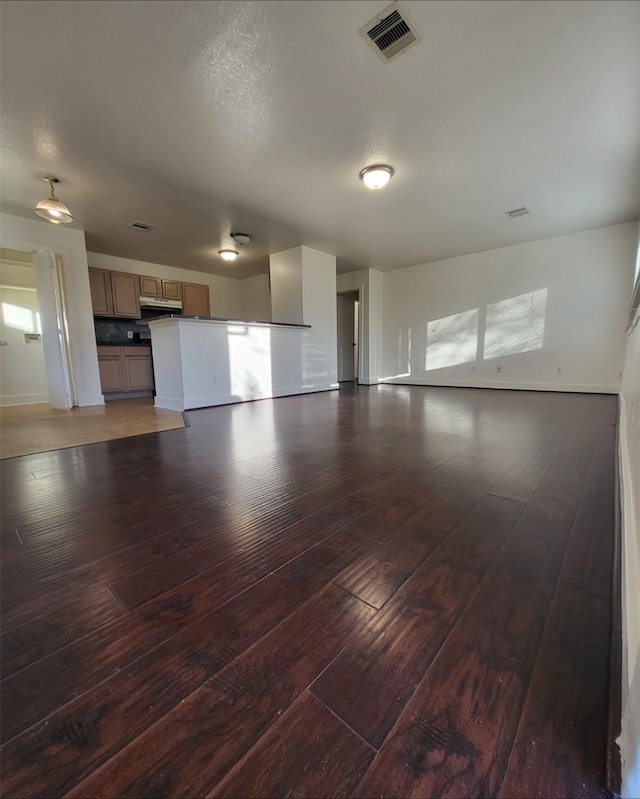 unfurnished living room with dark hardwood / wood-style flooring and a textured ceiling