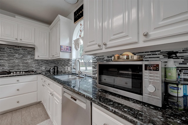 kitchen featuring sink, stainless steel appliances, tasteful backsplash, white cabinets, and dark stone counters