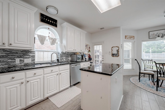 kitchen featuring white cabinetry, sink, dark stone countertops, a center island, and stainless steel appliances