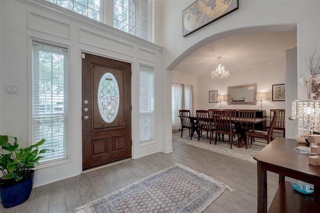 entrance foyer featuring crown molding, light hardwood / wood-style flooring, a chandelier, and a high ceiling