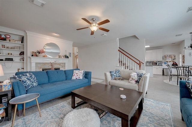 living room with a fireplace, ornamental molding, and ceiling fan