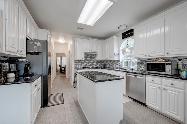 kitchen with dark stone countertops, appliances with stainless steel finishes, a kitchen island, and white cabinets