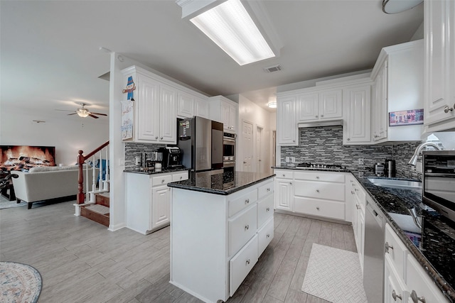 kitchen featuring white cabinetry, sink, dark stone counters, a center island, and stainless steel appliances