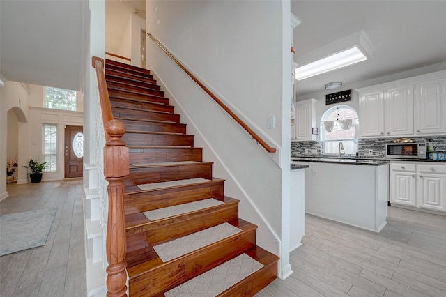 staircase featuring a towering ceiling and hardwood / wood-style floors