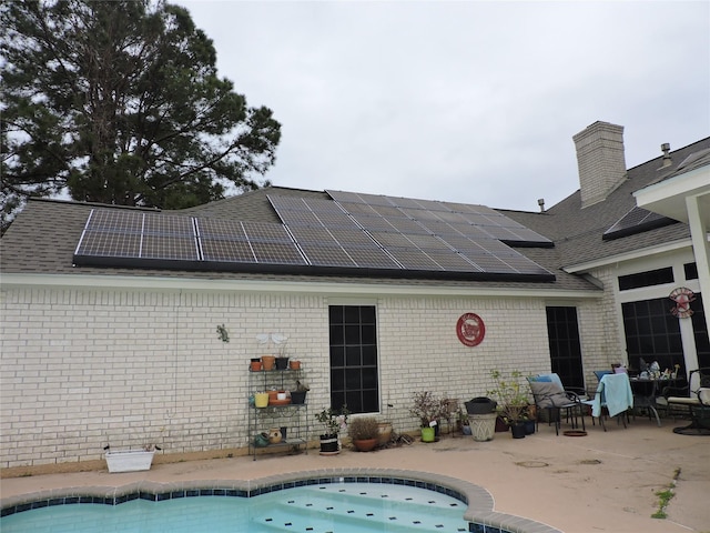 rear view of property featuring a patio and solar panels