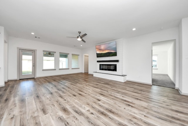 unfurnished living room with a fireplace, light hardwood / wood-style floors, and ceiling fan