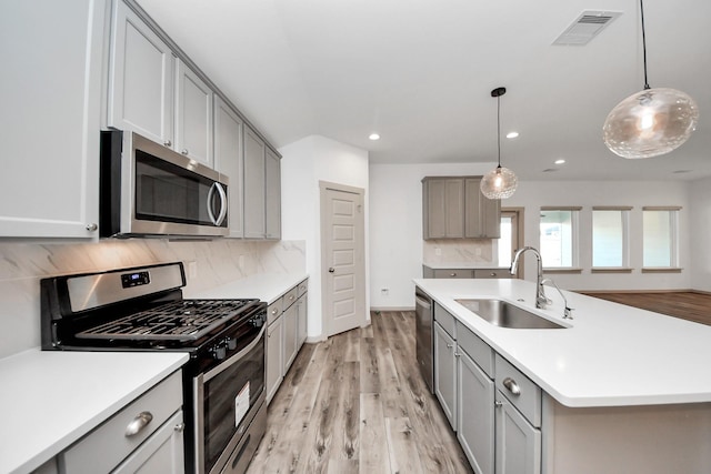 kitchen featuring sink, appliances with stainless steel finishes, gray cabinets, pendant lighting, and decorative backsplash