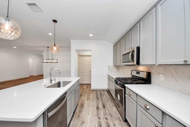 kitchen with sink, decorative light fixtures, gray cabinets, stainless steel appliances, and decorative backsplash