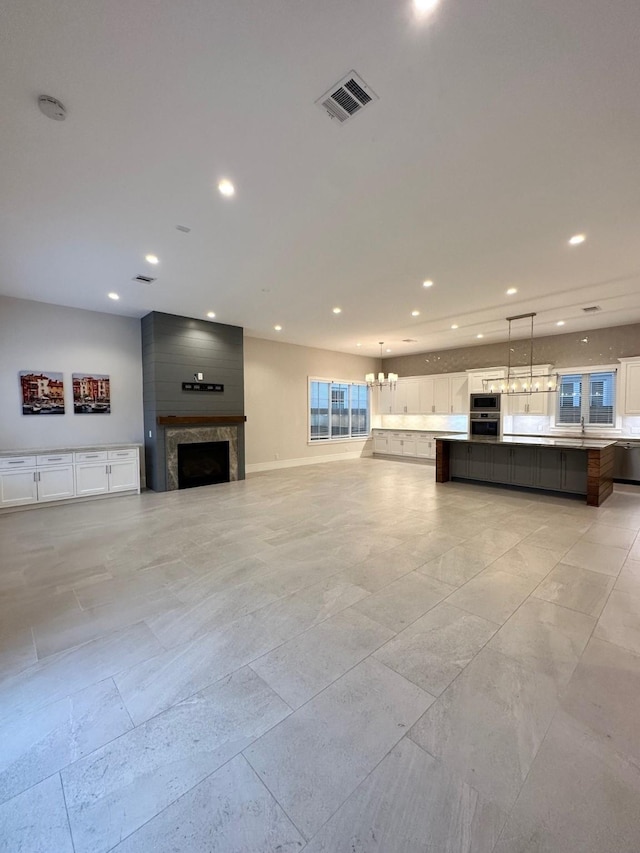 unfurnished living room with a notable chandelier and a large fireplace