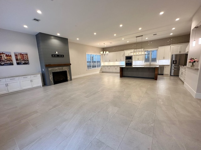 kitchen featuring pendant lighting, an inviting chandelier, stainless steel appliances, white cabinets, and a kitchen island