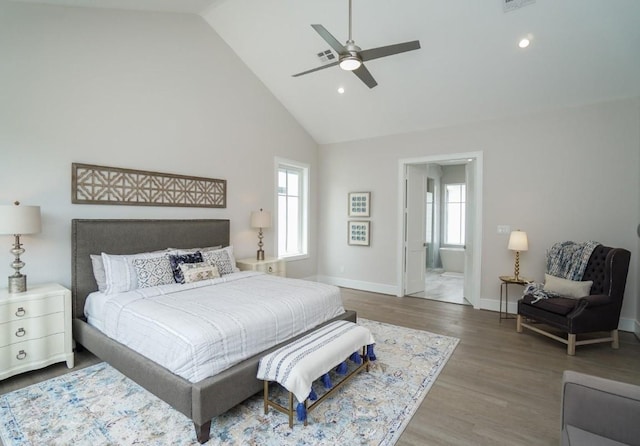 bedroom with wood-type flooring, ceiling fan, high vaulted ceiling, and ensuite bath