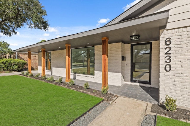 entrance to property with a porch and a yard