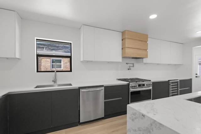 kitchen with stainless steel appliances, a wealth of natural light, sink, and white cabinets